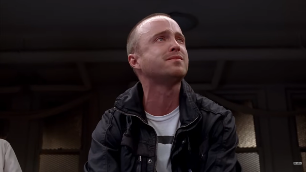 Jesse Pinkman in black jacket and white t-shirt crying and looking above at the side