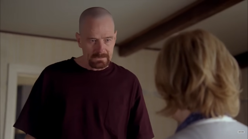 Walter White in red t-shirt looking at the sitting woman