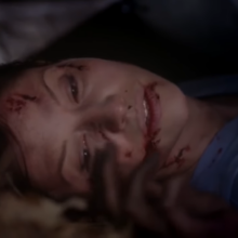 Wounded Lexie lies with her eyes opened and looks at the side